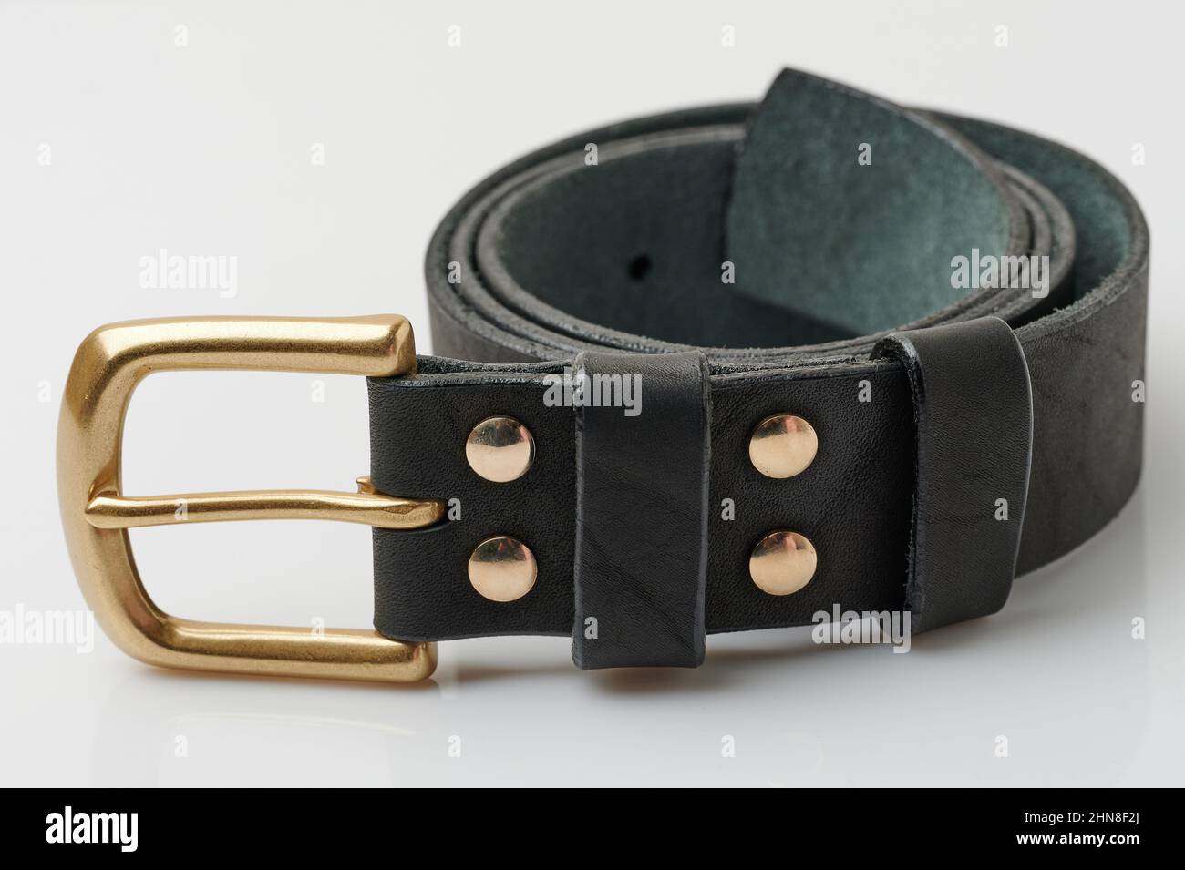 Rouleau de ceinture en cuir avec boucle dorée isolée sur fond de studio Banque D'Images