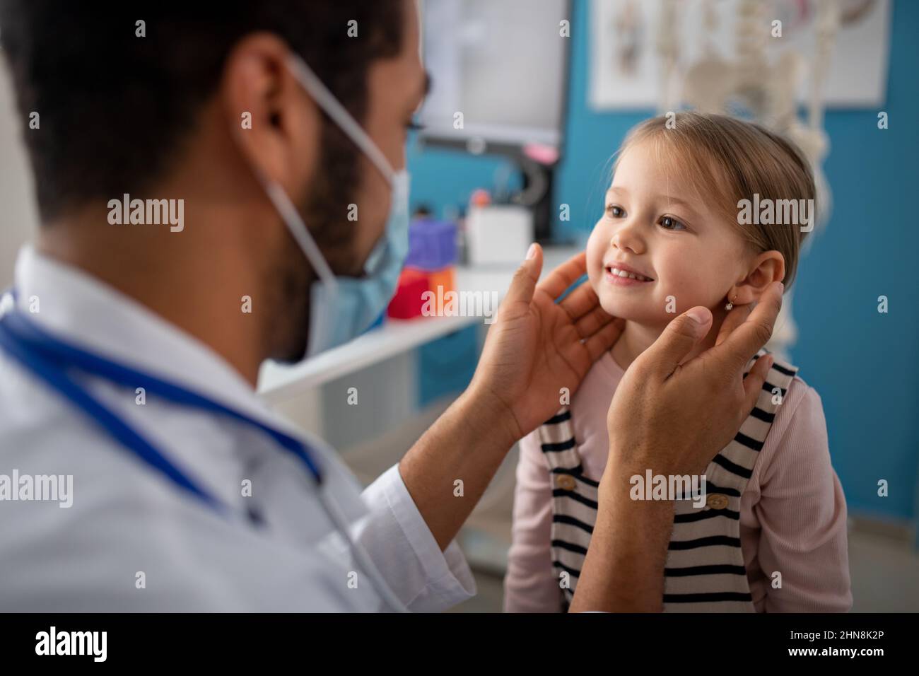 Jeune homme médecin vérifiant les ganglions lymphatiques de petite fille dans son bureau. Banque D'Images