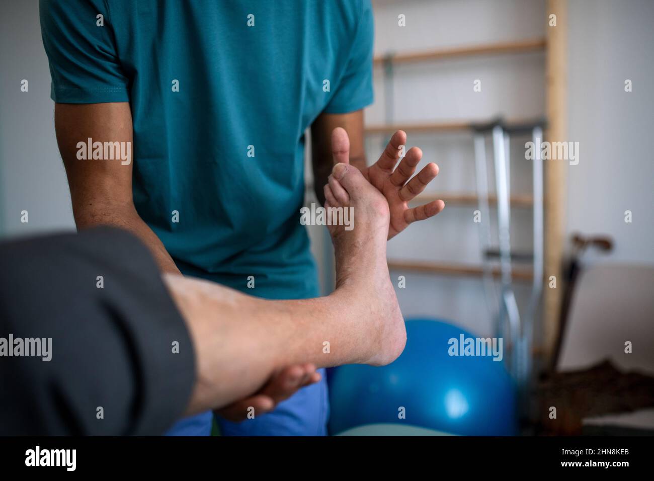Gros plan d'un physiothérapeute s'exerçant avec la jambe du patient âgé dans une salle de physiothérapie. Banque D'Images
