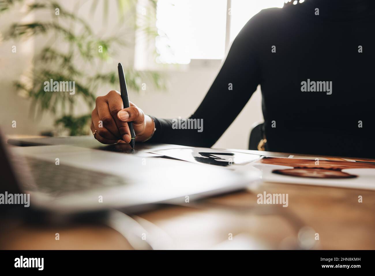 Une femme de créateur anonyme dessine sur une tablette graphique avec un stylet. Graphiste méconnaissable travaillant avec un ordinateur portable dans son bureau à domicile. CR Banque D'Images