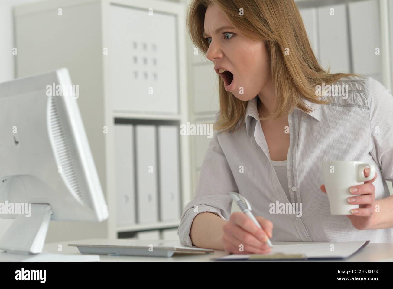 Jeune femme d'affaires en colère avec un ordinateur au bureau Banque D'Images