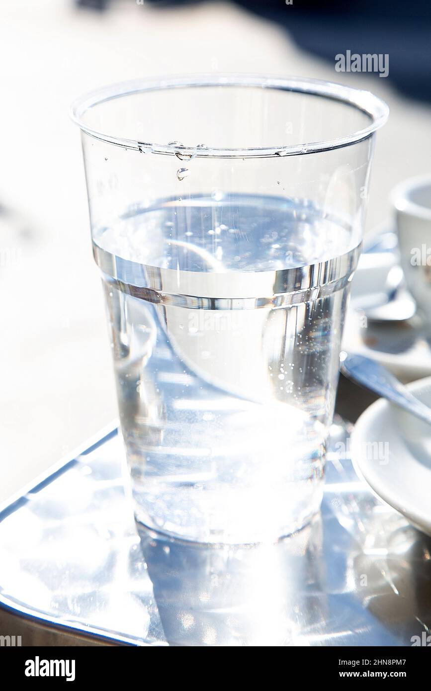 Verre en plastique transparent avec liquide non alcoolique sur table en métal dans le bar extérieur. Concept de problème d'eau potable. Un régime sain. Banque D'Images