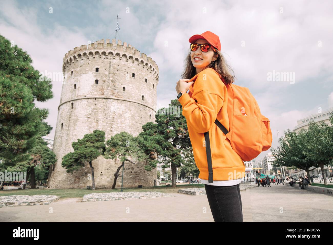 Une heureuse femme voyageur avec sac à dos se dresse sur le point de vue et bénéficie du panorama de la tour blanche dans la ville de Thessalonique en Grèce Banque D'Images