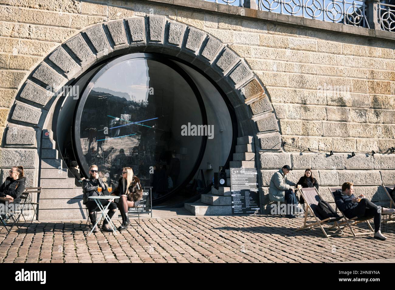 Un café-bar au bord de la rivière avec une grande porte en verre circulaire à Prague. Banque D'Images
