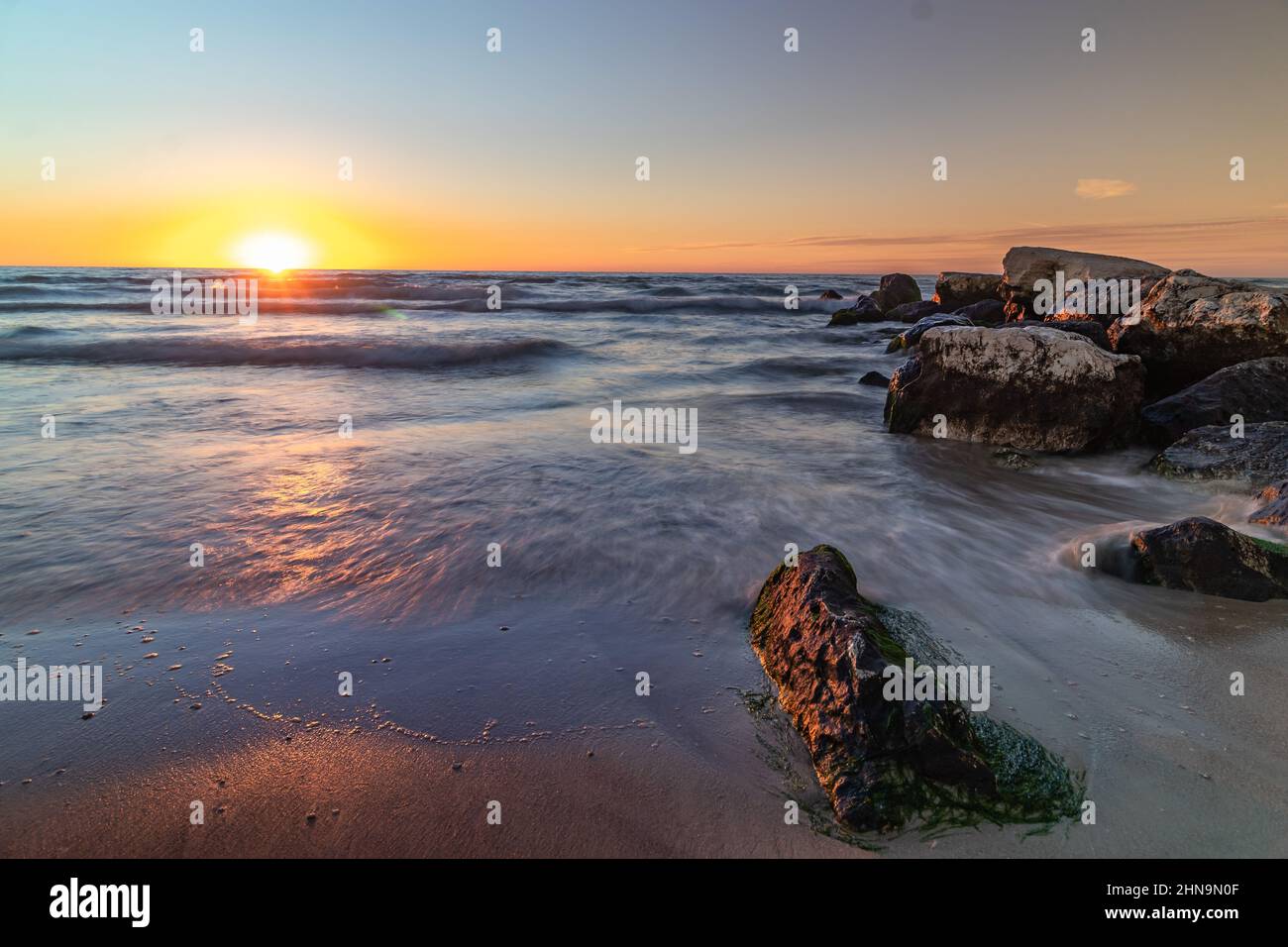 Vue large à angle bas des vagues qui s'écrasant sur les rochers au coucher du soleil sur la mer Poleg Beach Israël. Banque D'Images