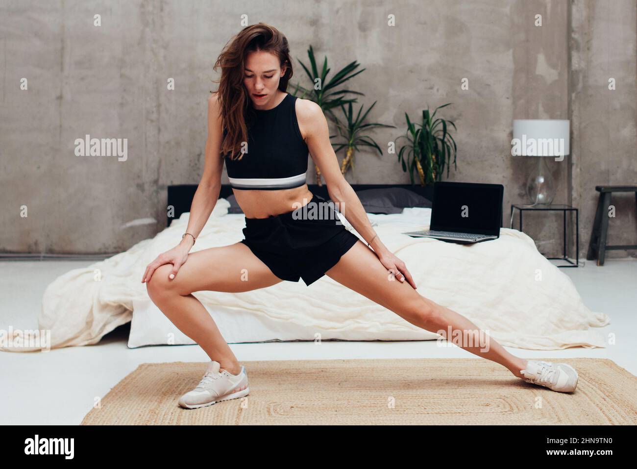 Femme pratiquant à la maison faisant des exercices d'étirement de jambe. Banque D'Images