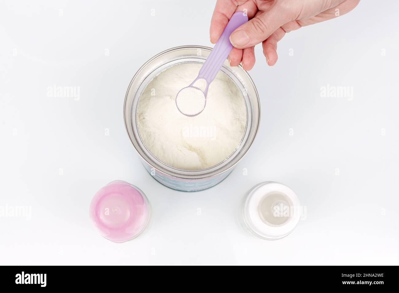 Préparation du mélange d'alimentation de bébé sur fond blanc. Vue de dessus. Gros plan de la main de la mère préparant la préparation de la préparation du lait maternisé Banque D'Images