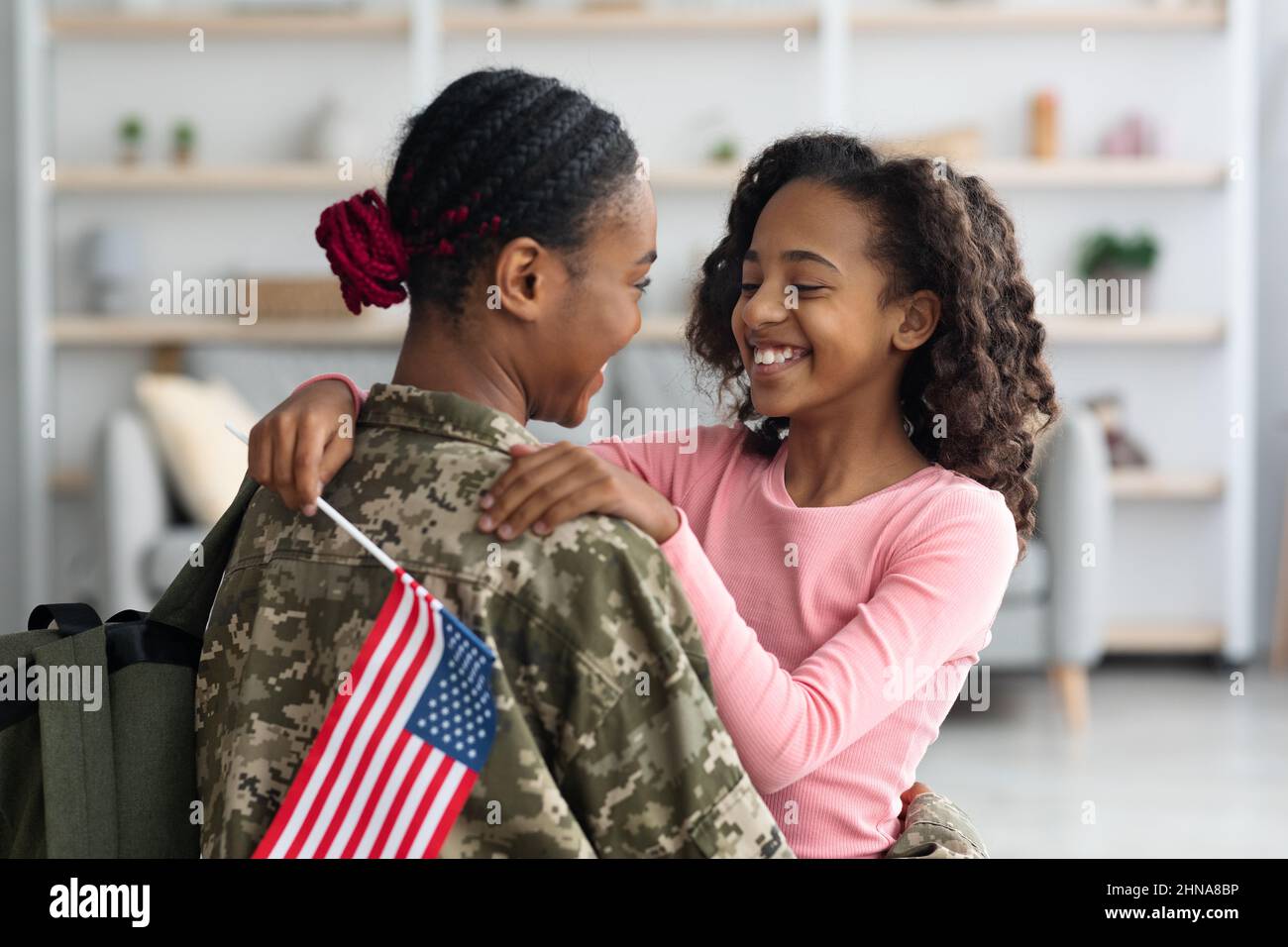 Fille gaie avec drapeau des États-Unis embrassant sa mère Banque D'Images
