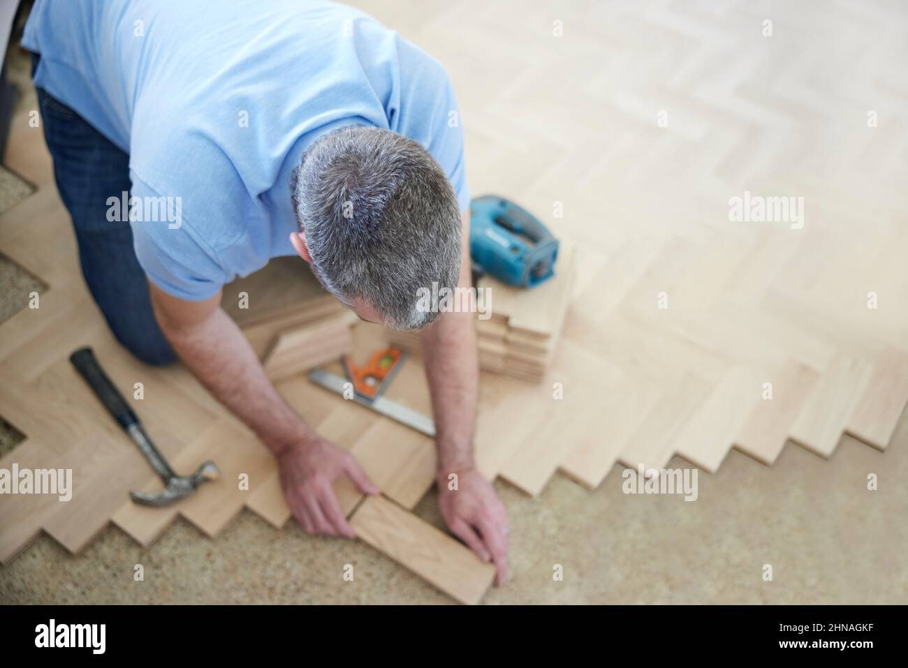 Vue de dessus de Carpenter ou constructeur pose de nouveau bloc de bois parquet plancher dans la cuisine à la maison Banque D'Images