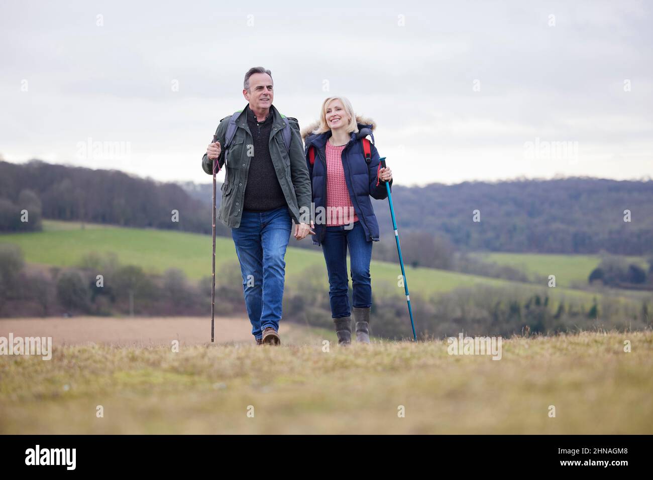 Couple d'âge mûr marchez dans la campagne d'automne ou d'hiver en utilisant des bâtons de randonnée Banque D'Images