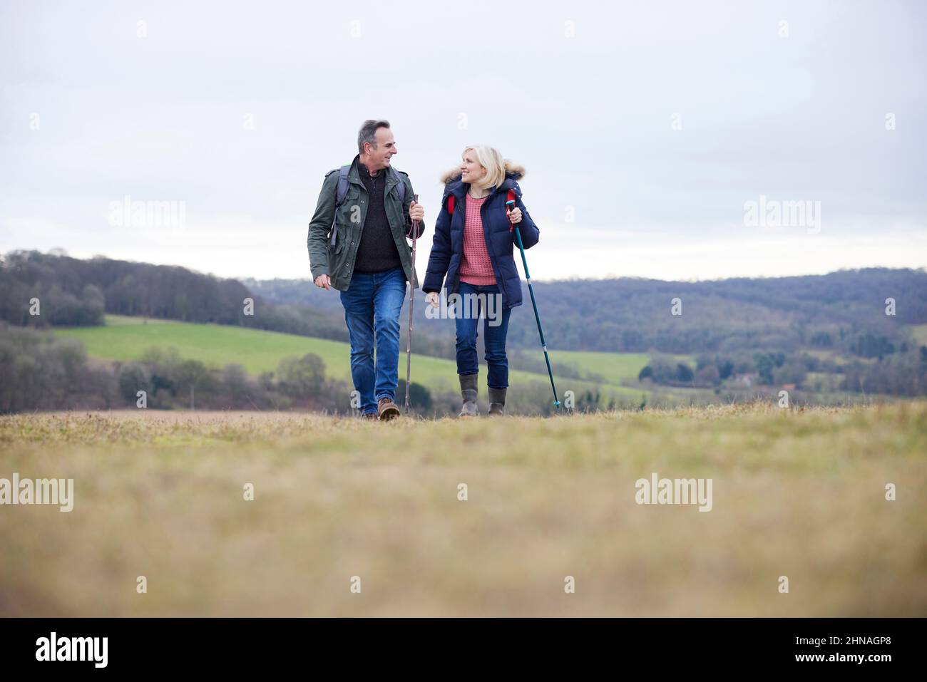 Couple d'âge mûr marchez dans la campagne d'automne ou d'hiver en utilisant des bâtons de randonnée Banque D'Images