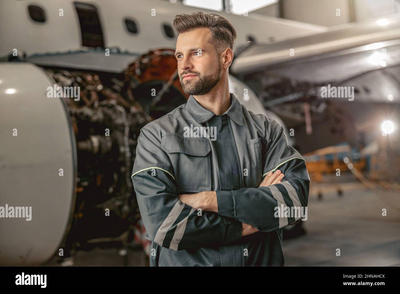 Homme barbu ingénieur de maintenance d'avion debout dans le hangar Banque D'Images