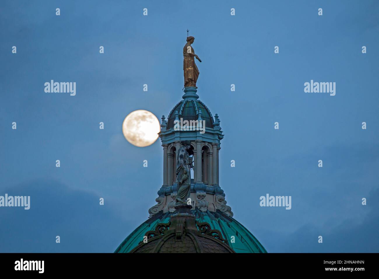 Édimbourg, Écosse, Royaume-Uni. 15th février 2022. Snow Moon Rising qui sera un 100% complet demain, apparaissant dans le ciel derrière la statue représentant la renommée au-dessus du dôme octogonal central de l'ancien siège de la Banque d'Écosse sur le Mound. Temps très nuageux avec des écarts occasionnels dans le nuage et la température de 4 degrés centigrade et de fortes pluies juste après cette prise de vue. Banque D'Images