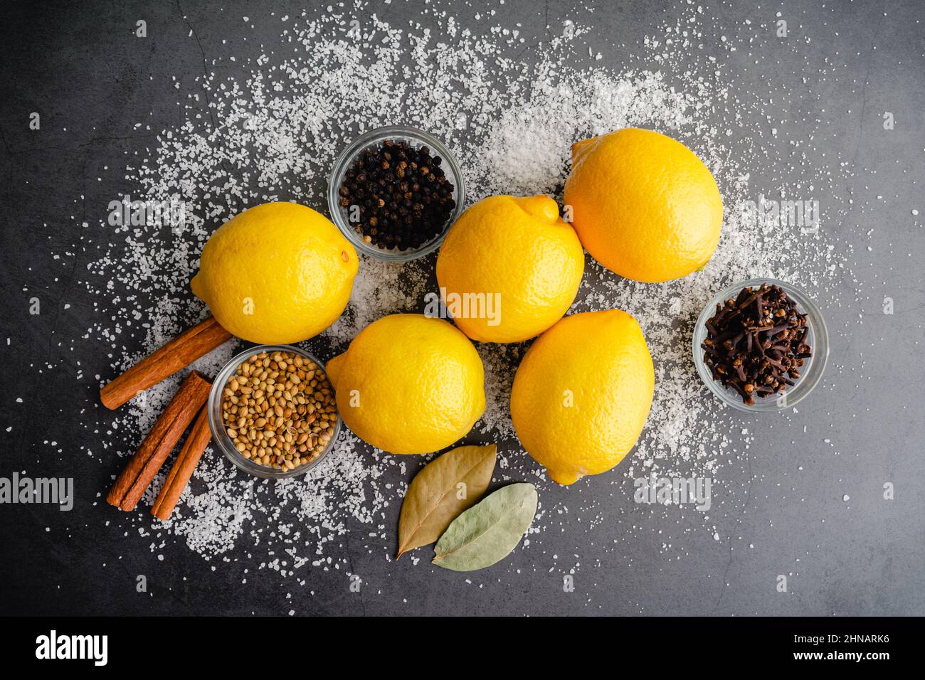 Ingrédients utilisés pour faire des citrons conservés : citrons frais, épices entières et sel casher sur fond sombre Banque D'Images