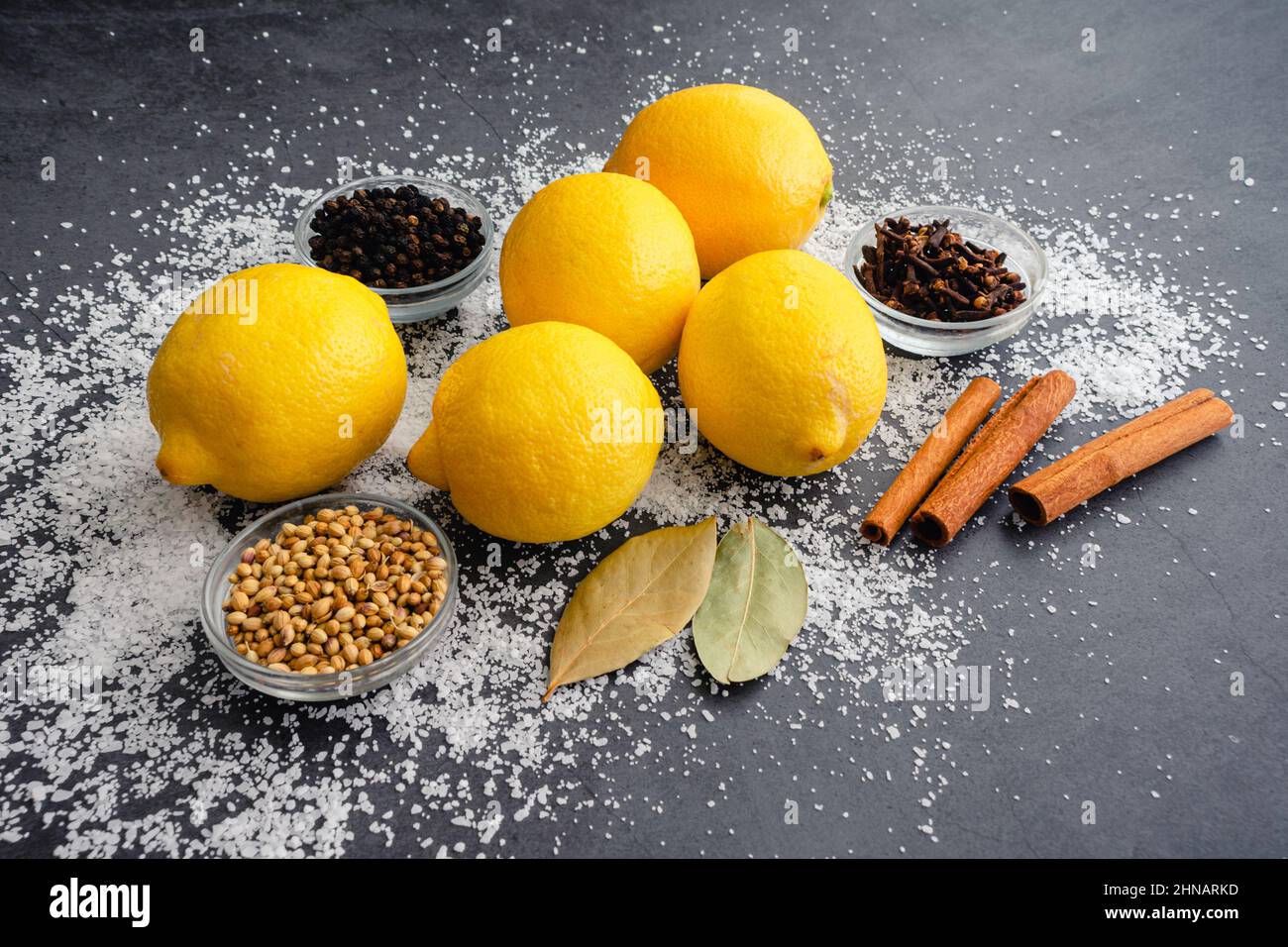 Ingrédients utilisés pour faire des citrons conservés : citrons frais, épices entières et sel casher sur fond sombre Banque D'Images