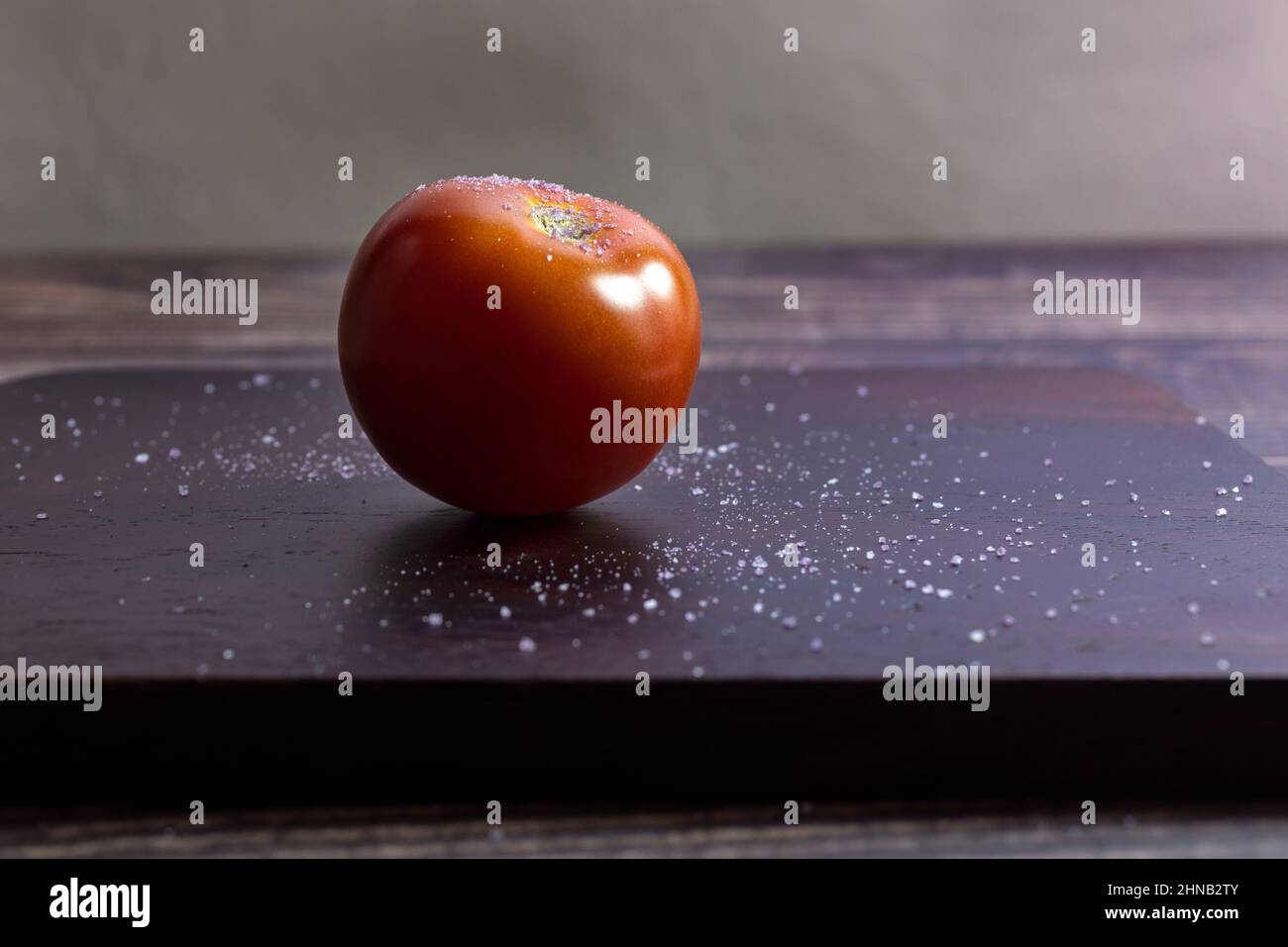 Planche à découper en bois avec une tomate salée Banque D'Images