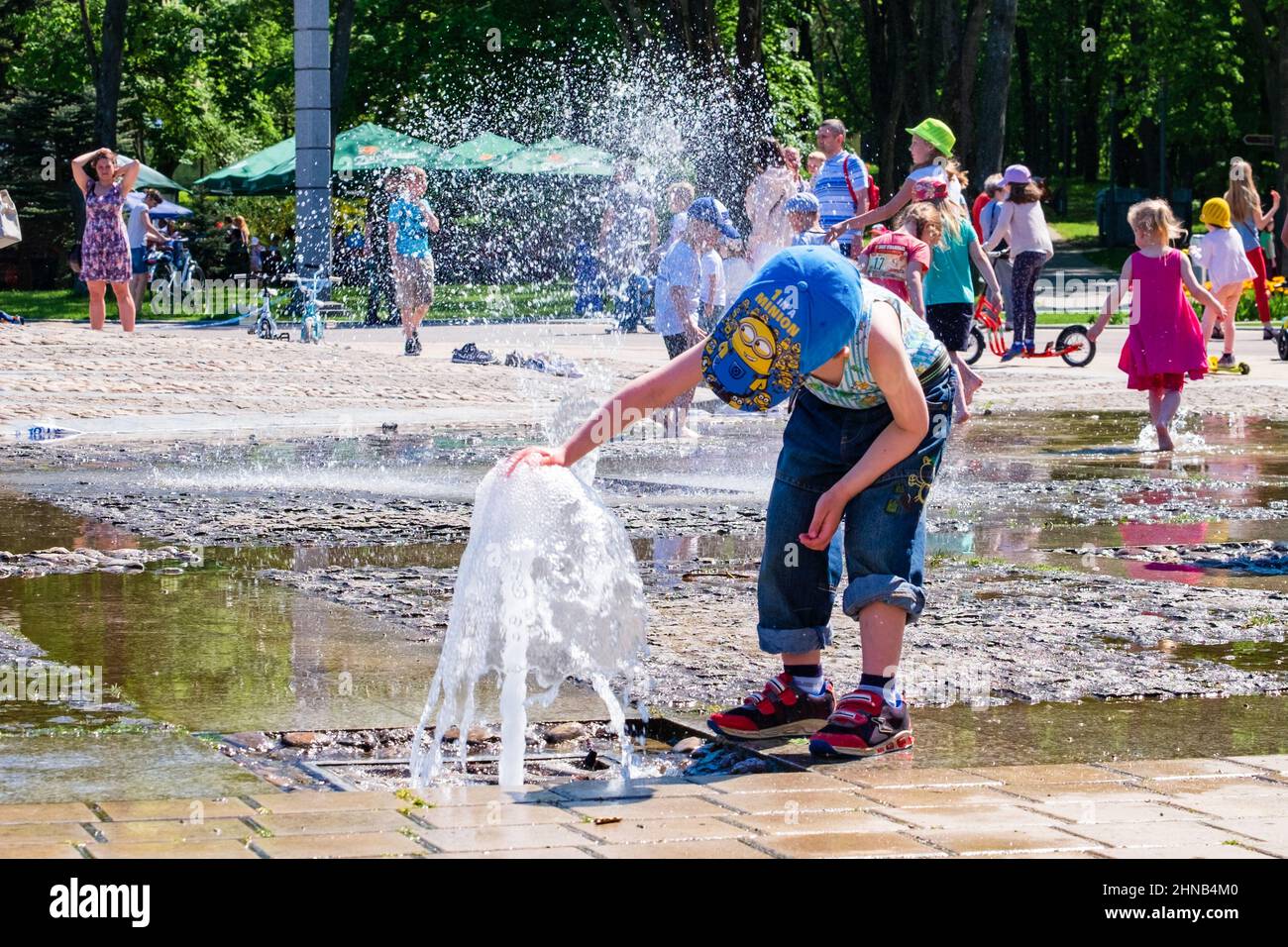 Les enfants s'amusent dans la fontaine lors d'une journée ensoleillée et chaude dans le parc de la ville Banque D'Images