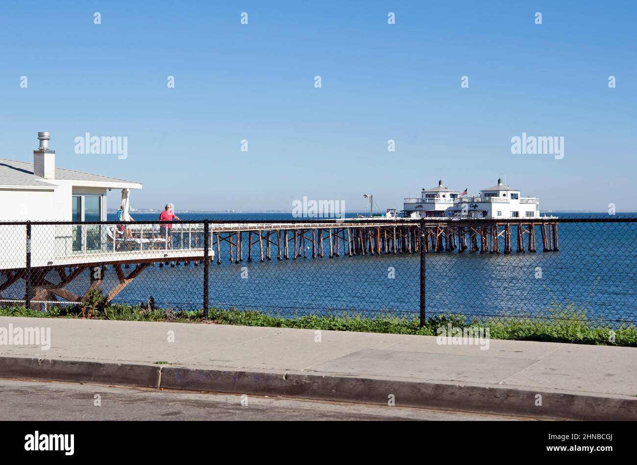 Homme sur le balcon de la maison de plage donnant sur la jetée de Malibu. Banque D'Images