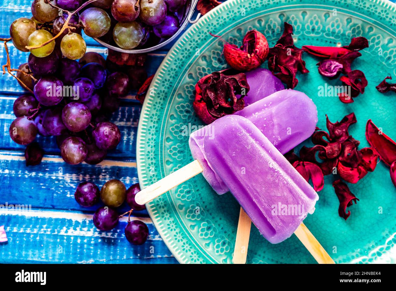 Une glace au raisin de style Lollipop sur un bâton sur une assiette vintage sur une table en bois bleu clair. Concept d'alimentation naturelle et saine. CopySpace. Banque D'Images