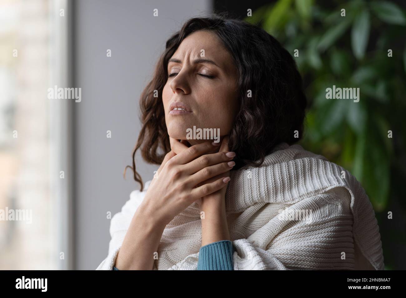Contrarié malade femme debout à la maison touchant les glandes du cou gonflées, ayant mal à la gorge du virus Banque D'Images
