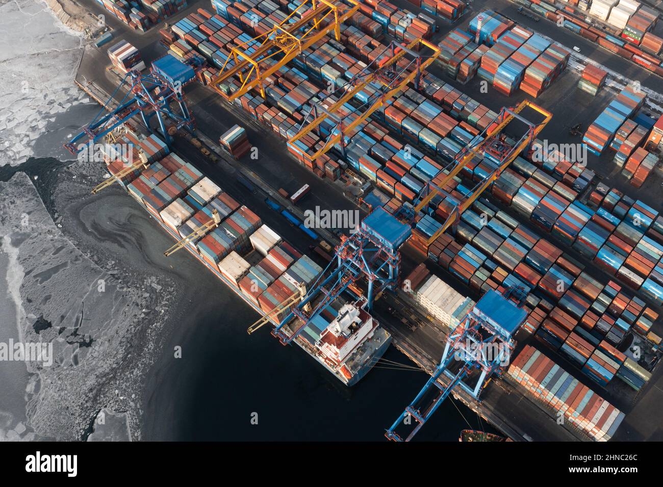 Vladivostok, Russie - 26 janvier 2022 : Vue de dessus du terminal des conteneurs du port maritime.En hiver, un bateau à conteneurs est en train de charger à l'embarcadère. Banque D'Images