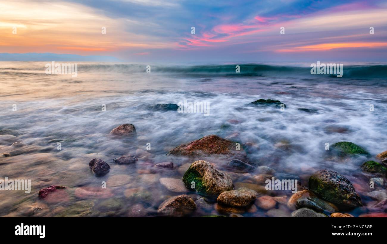 Un paysage océanique avec des rochers de mer dans l'avant-sol et Un ciel de coucher de soleil coloré au format d'image haute résolution 16,9 Banque D'Images