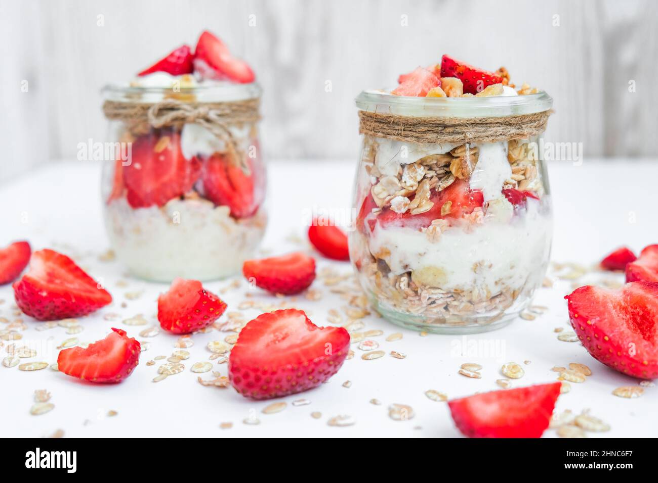 Petit déjeuner sain. Flocons d'avoine Granola au yaourt grec et aux noix muesli aux fraises en pots sur fond clair. Végétalien, végétarien et régime de perte de poids Banque D'Images