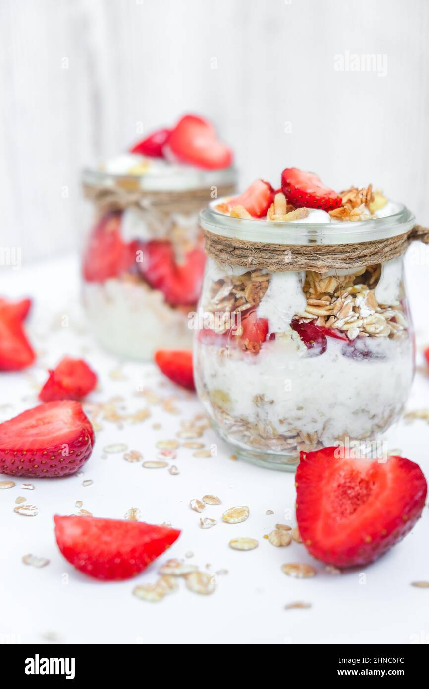 Petit déjeuner sain. Flocons d'avoine Granola au yaourt grec et aux noix muesli aux fraises en pots sur fond clair. Végétalien, végétarien et régime de perte de poids Banque D'Images