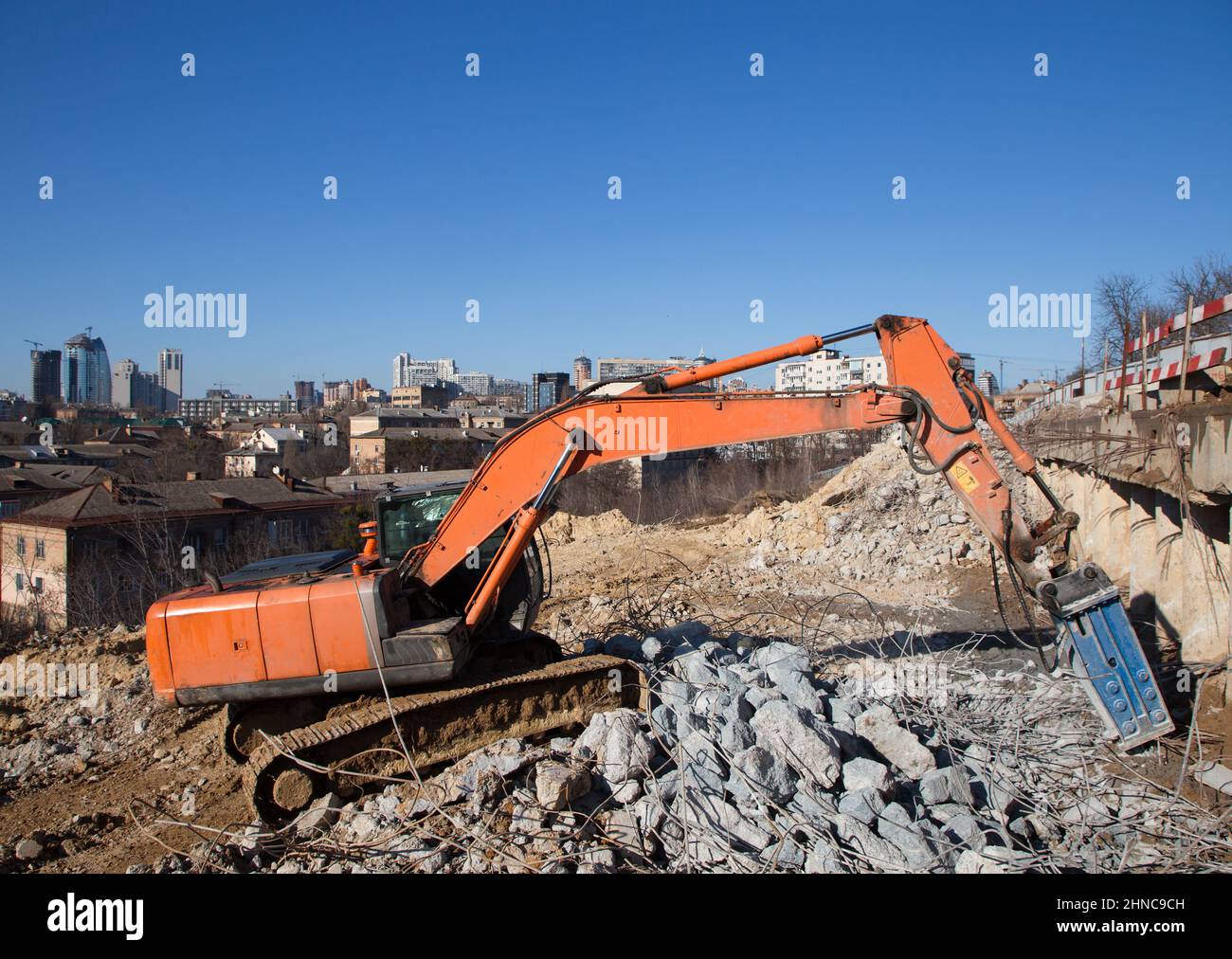 la pelle hydraulique orange avec un marteau hydraulique industriel sur un chantier de construction effectue le démontage des structures en béton armé. Autour de fr Banque D'Images