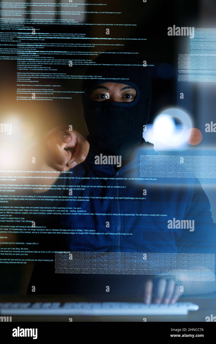 Vous ne savez jamais qui vous regarde en ligne. Photo d'un pirate craquant un code informatique dans l'obscurité. Banque D'Images