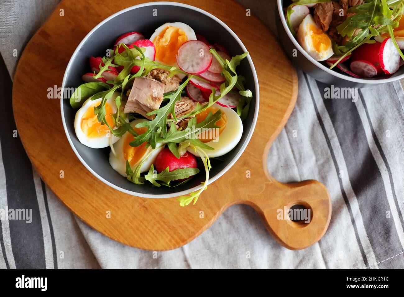 Salade fraîche avec thon, radis, œufs, arugula d sur fond gris vue de dessus. Une alimentation saine. Salade de printemps Banque D'Images