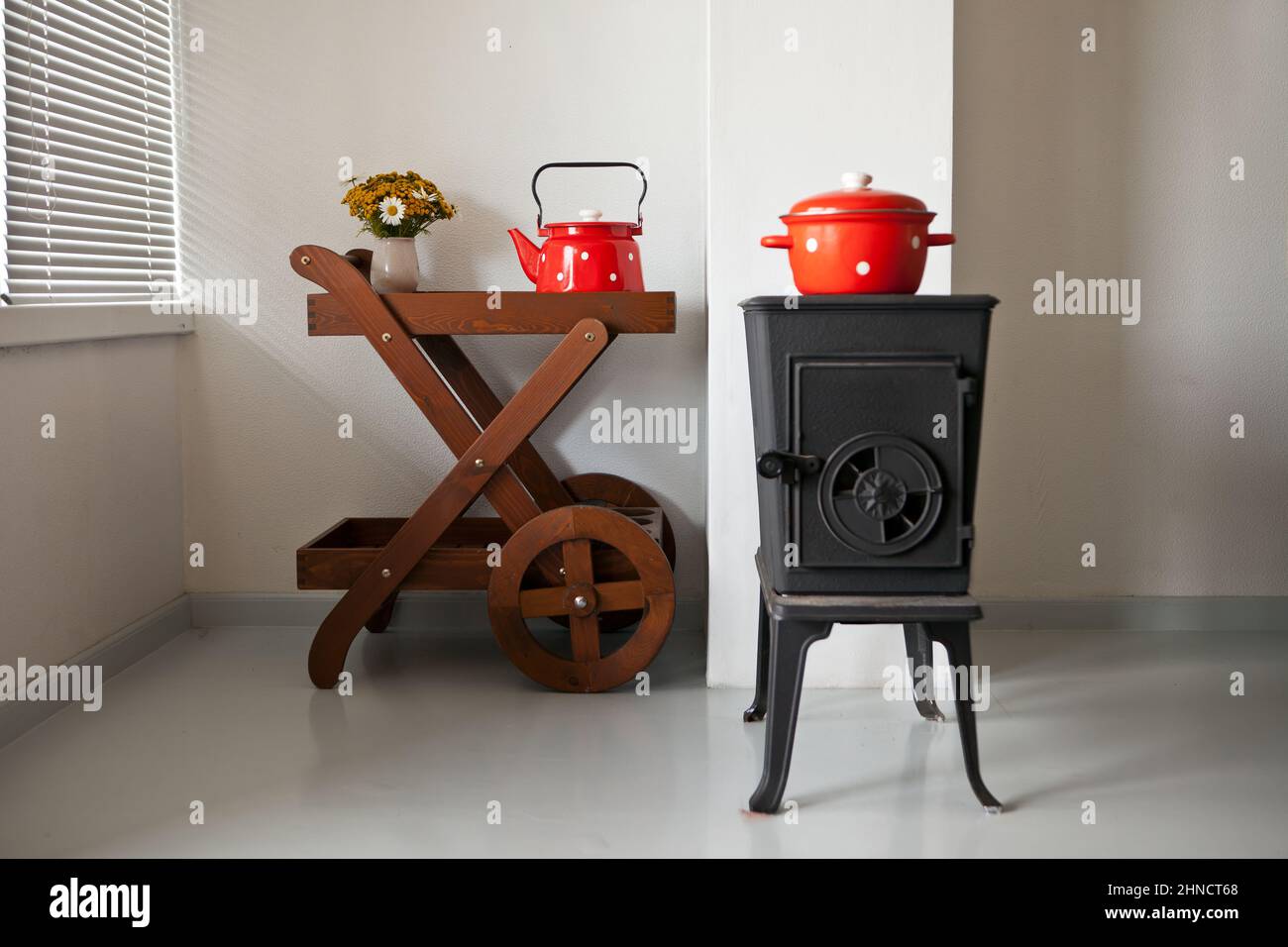 poêle à repasser à l'intérieur de la maison dans la maison de campagne. four chauffé près de la fenêtre. vaisselle rouge sur la table Banque D'Images