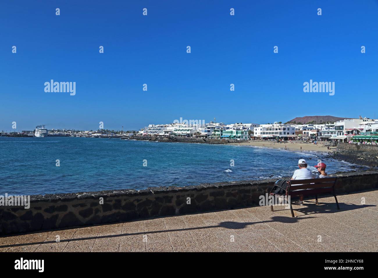 Un couple senior s'est assis sur le banc pour admirer la vue sur Playa Blanca, à Lanzarote Banque D'Images