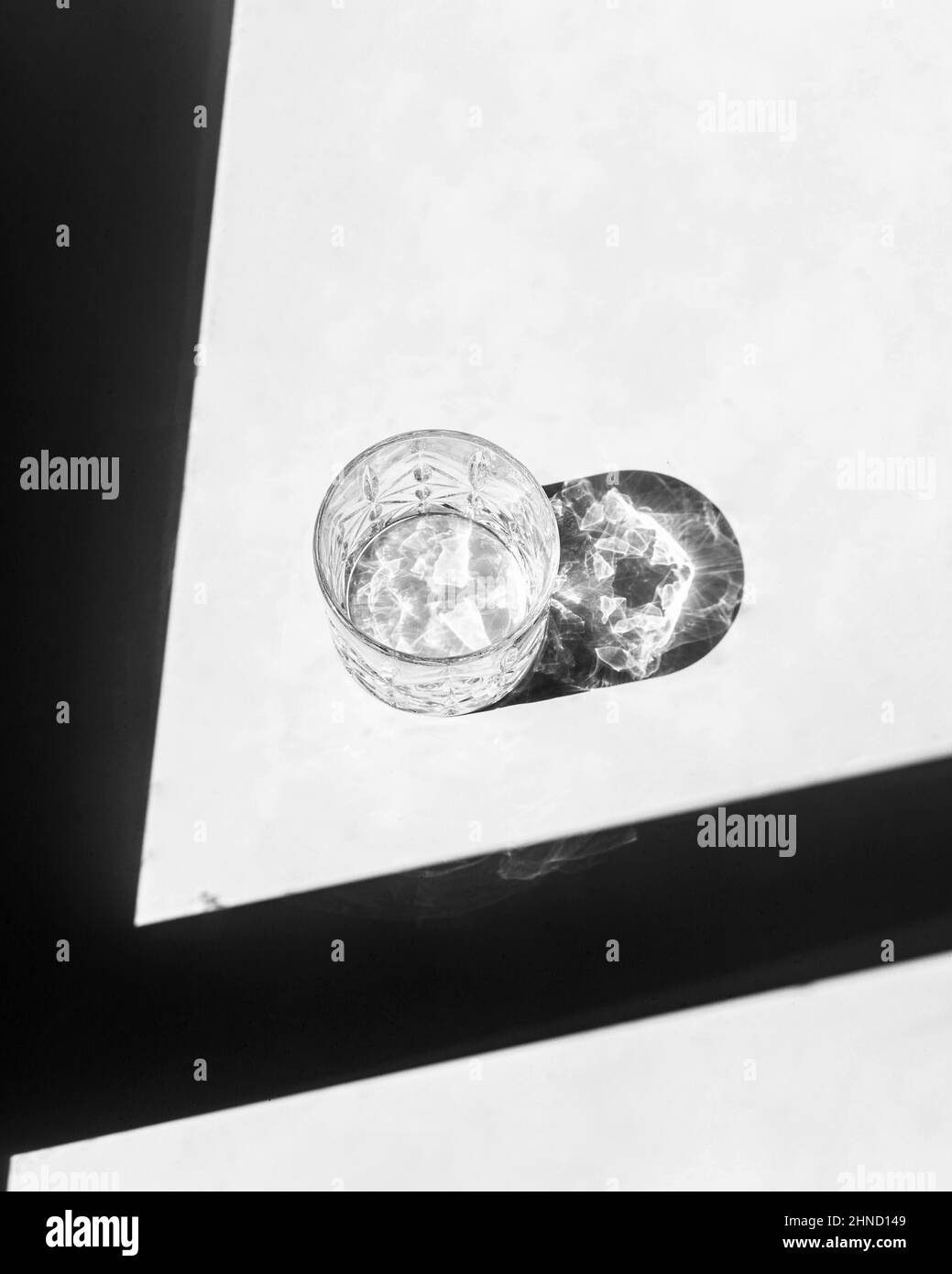 De dessus, verre à bille basse vide placé sur une table blanche près de l'ombre et réfléchissant la lumière du soleil en journée Banque D'Images