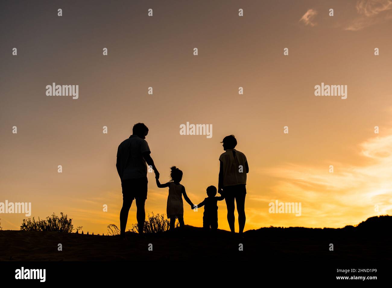 Silhouette de famille positive non reconnaissable avec son fils et sa fille adorables qui se promenent sur le mont contre le ciel du coucher du soleil le jour de l'été Banque D'Images