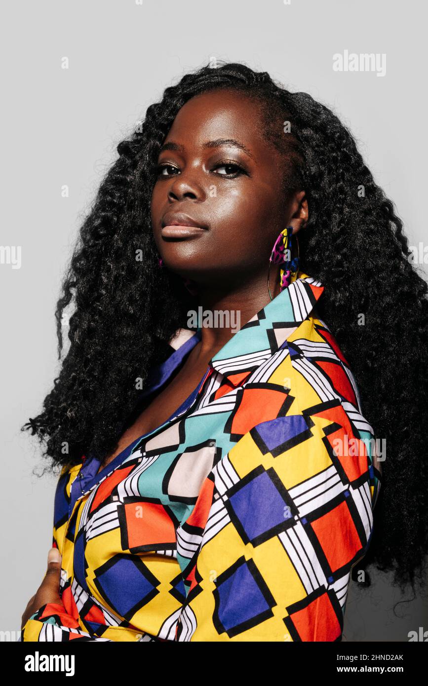 Portrait d'une femme afro-américaine avec des cheveux bouclés et des vêtements colorés sur fond blanc Banque D'Images