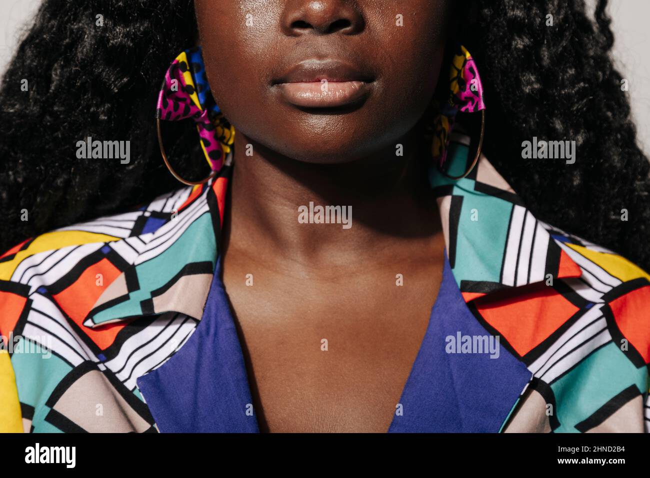 Femme afro-américaine écourtée avec des cheveux bouclés et des vêtements colorés sur fond blanc Banque D'Images