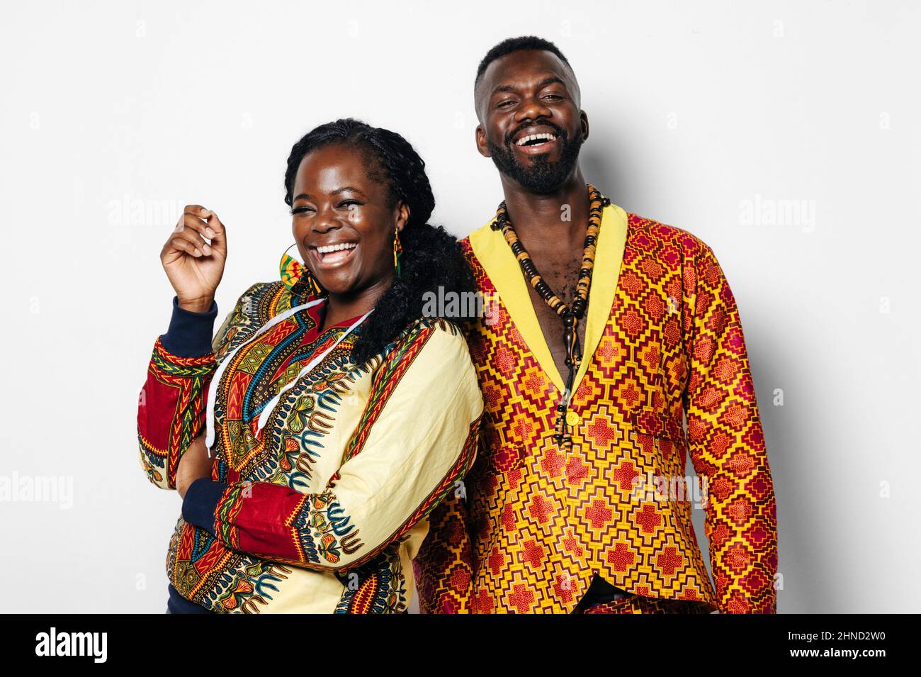 Couple joyeux dans une élégante tenue africaine debout sur fond blanc et regardant l'appareil photo Banque D'Images