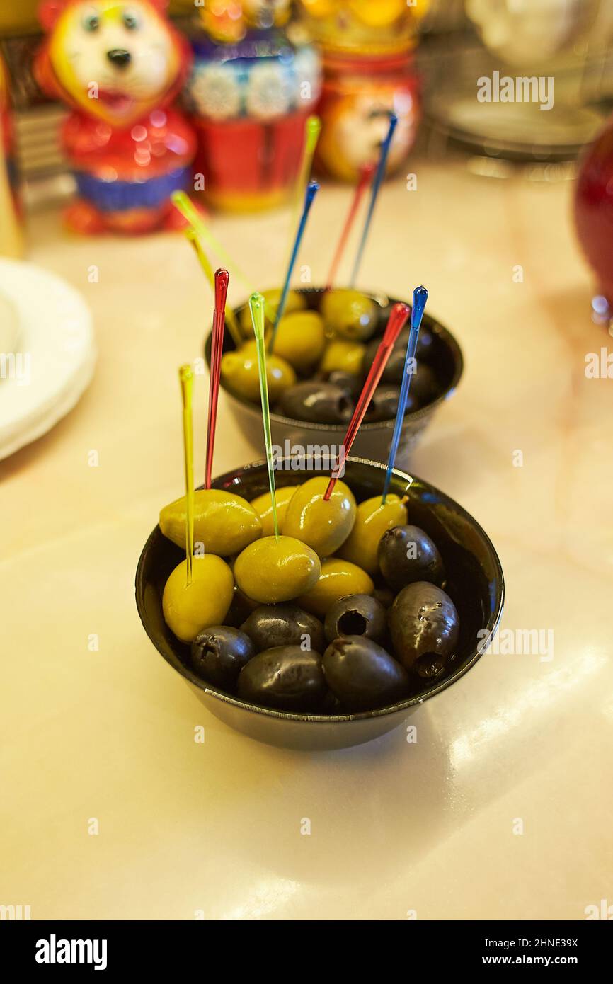 Hors-d'œuvre. Olives vertes et noires servies dans des verres noirs sur une table en marbre. Banque D'Images