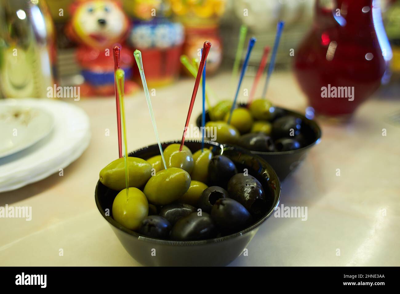 Hors-d'œuvre. Olives vertes et noires servies dans des verres noirs sur une table en marbre. Banque D'Images