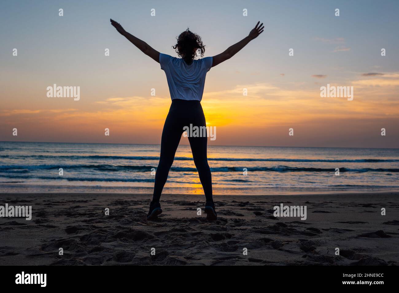 Jeune femme méconnaissable faisant du sport sur la plage au coucher du soleil Banque D'Images