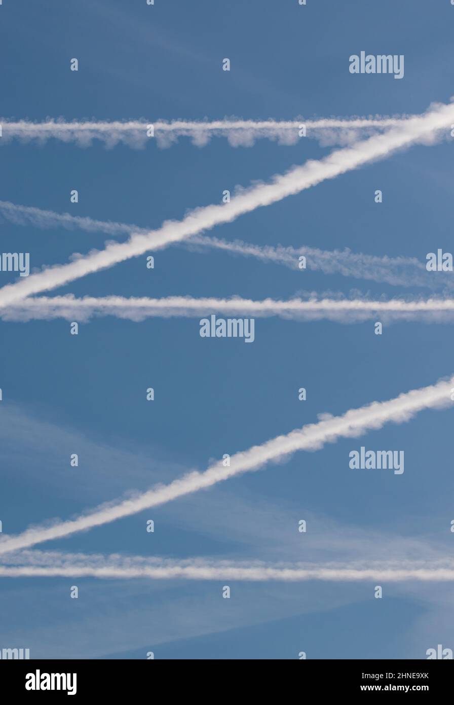 Retournez au voyage aérien alors que les contrailles de l'avion dessinent des lignes blanches à travers le ciel bleu. Un motif parfait est dessiné à travers le ciel tandis que les restrictions Covid se lèvent Banque D'Images