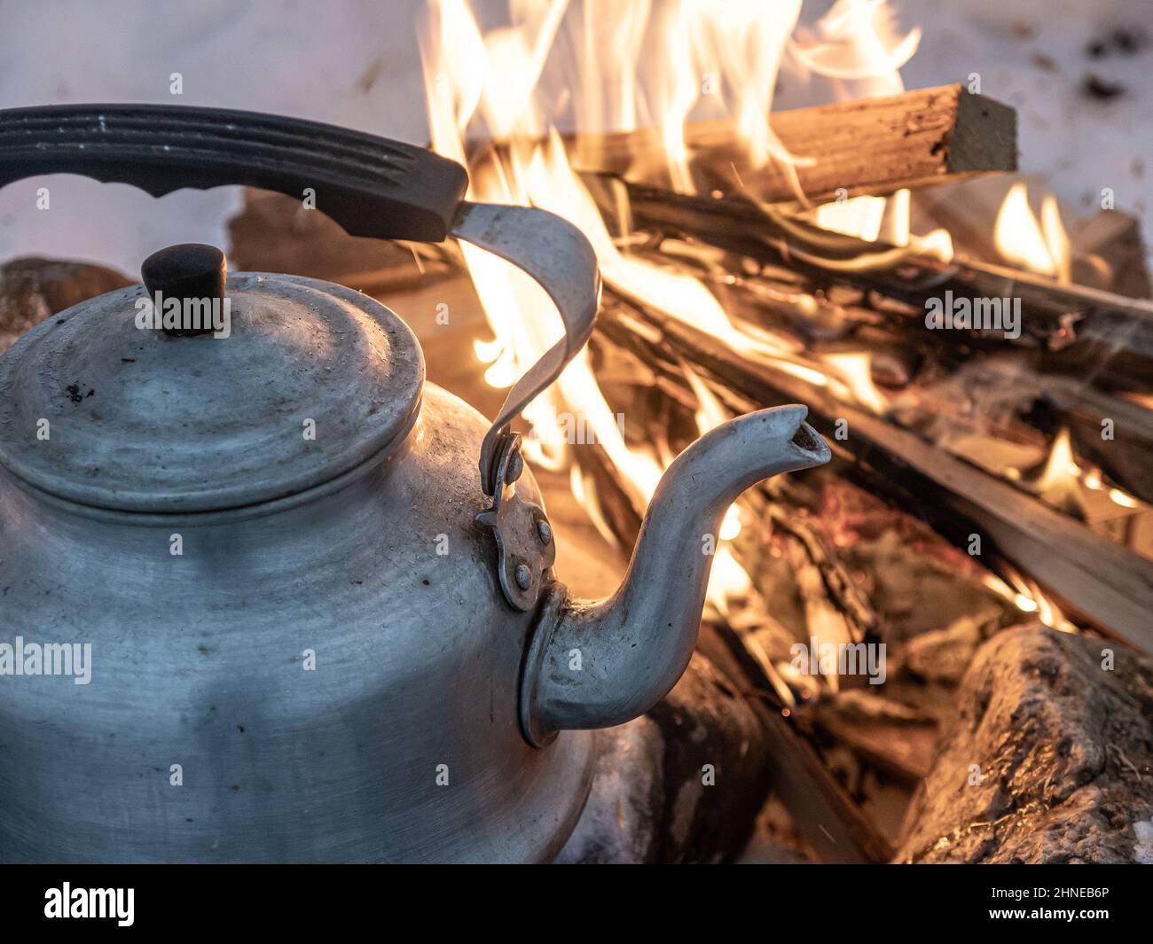 Camping d'hiver avec bouilloire en acier et feu vivant dans un cadre de neige Banque D'Images