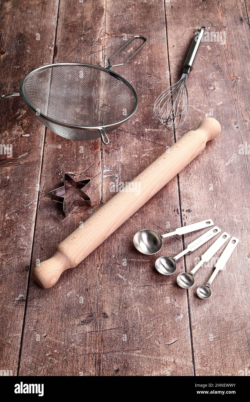 Table de cuisine en bois avec broche à roulettes, tamis, couteau à pâtisserie, fouet et cuillères à mesurer, concept de cuisson Banque D'Images