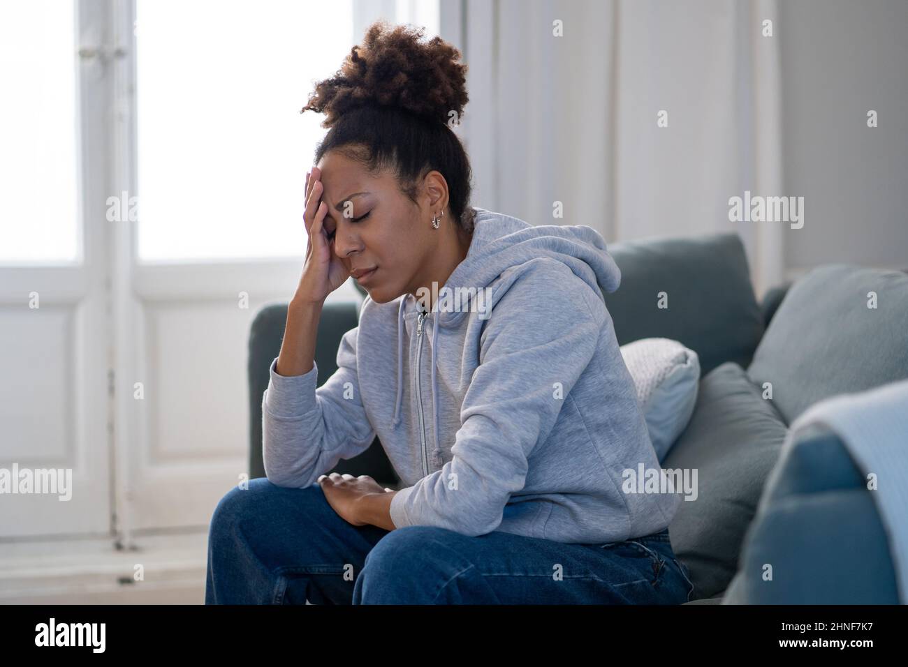 Une jeune femme afro-américaine attractive et dépressive, couchée sur un canapé à la maison, se sentant triste fatiguée et inquiète, souffrant de dépression, de stress et d'anxiété Banque D'Images