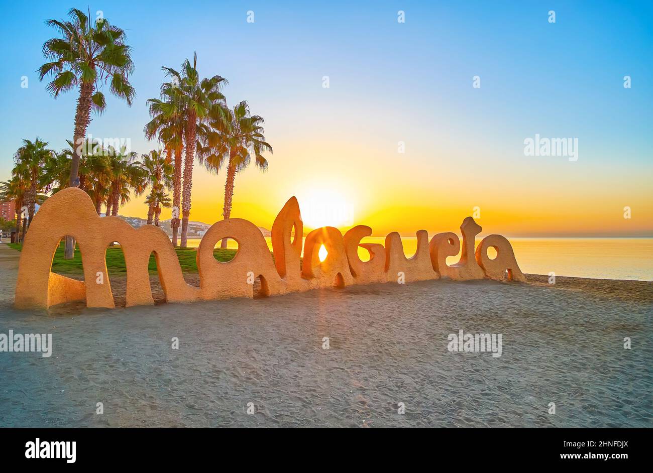 MALAGA, ESPAGNE - 28 SEPTEMBRE 2019 : le soleil lumineux de l'aube brille à  travers le signe Malmetagueta sur la plage de sable avec de grands palmiers  et la mer dorée Photo Stock - Alamy