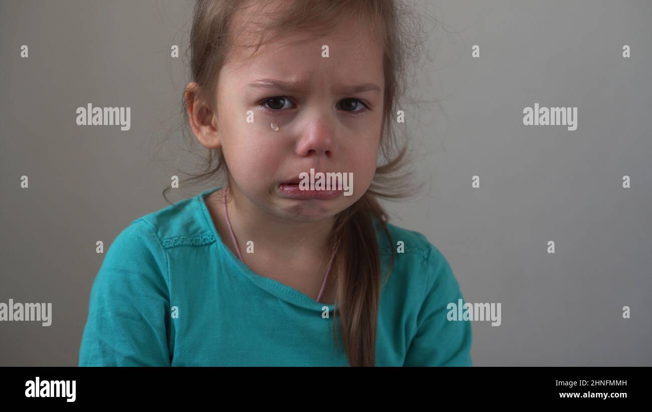 Portrait petite fille triste bouleversé enfant éclate en larmes cries sob regardant l'appareil photo à l'intérieur. Enfants sincères émotions sentiments à la maison pleurant enfant avec Banque D'Images