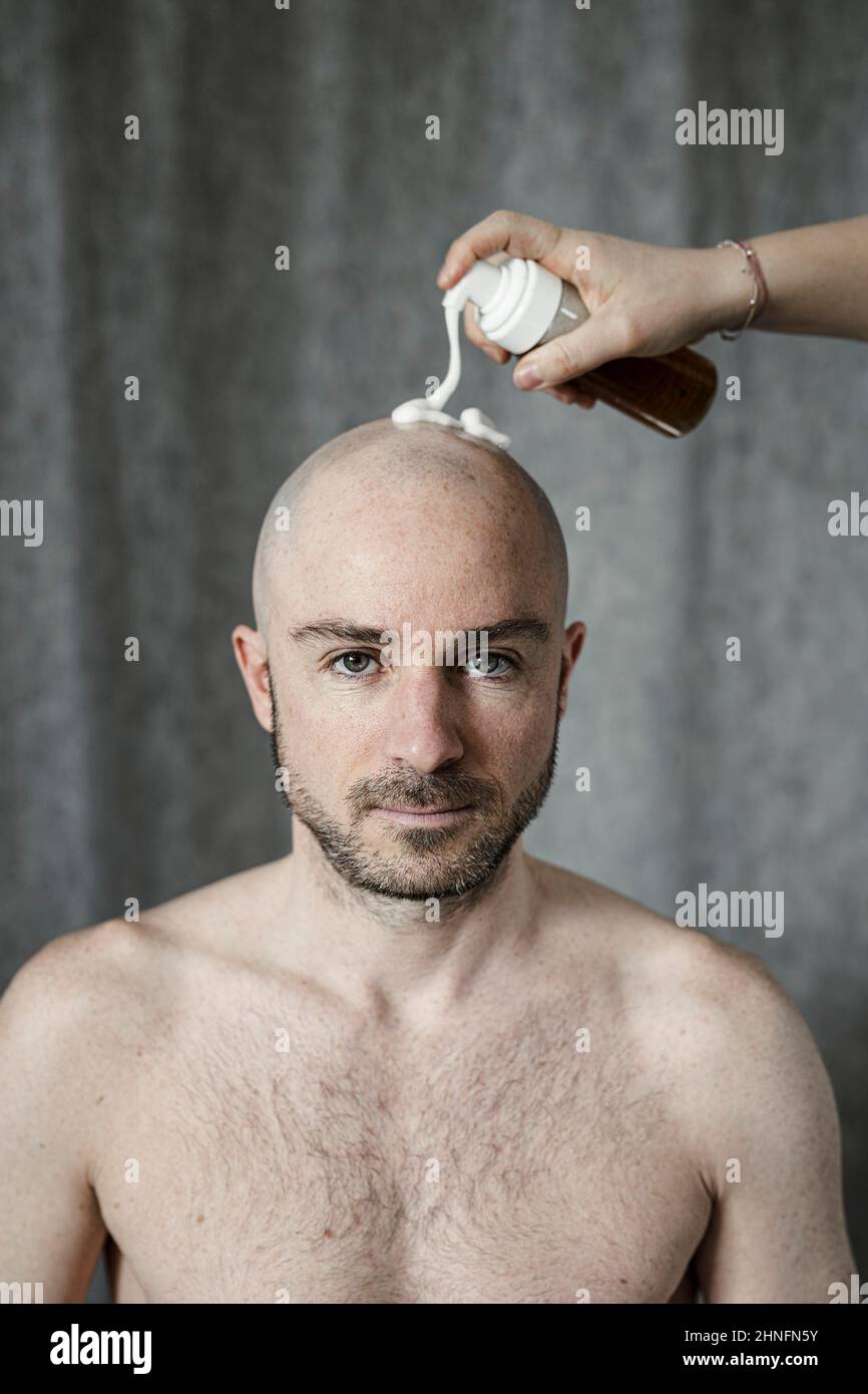 L'homme reçoit de la mousse de rasage pulvérisée sur sa tête chauve Banque D'Images