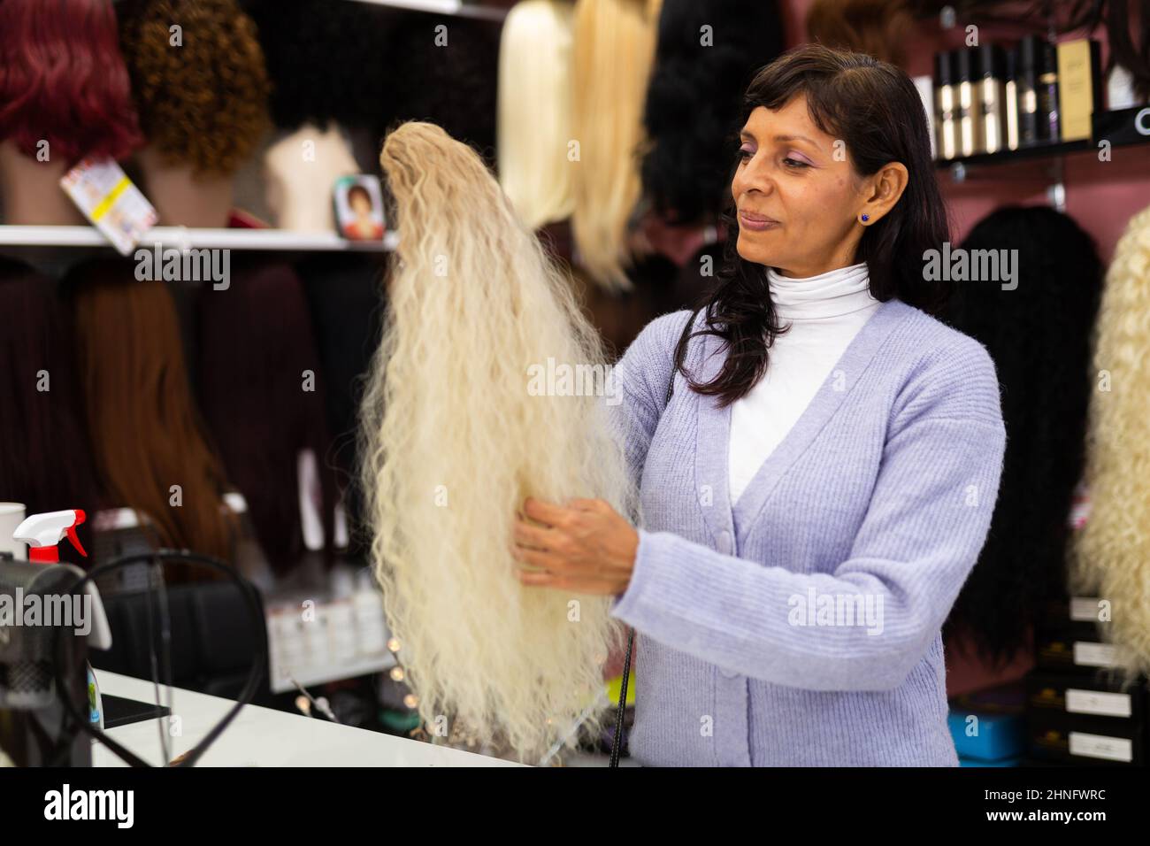 Femme choisissant la perruque naturelle à la boutique spécialisée Banque D'Images