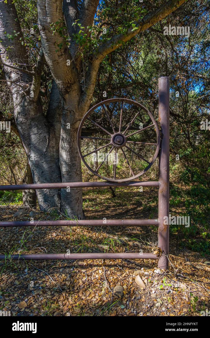 Roue métallique rustique attachée à une clôture en métal sur le ranch historique de dos Pueblos, vue de South dos Pueblos Road dans le comté de Santa Barbara, CA Banque D'Images